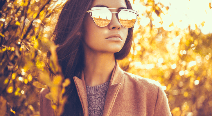 Woman wears mirrored sunglasses during fall.